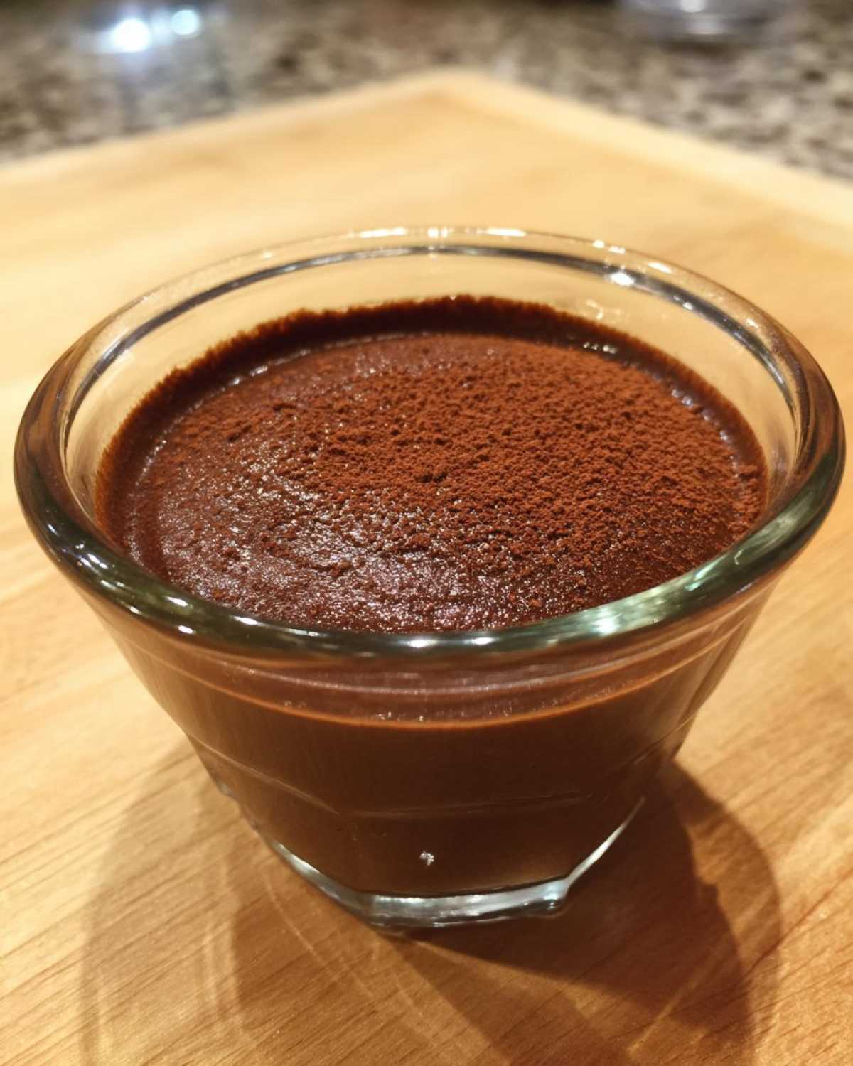 A close-up of rich Vegan Chocolate Avocado Mousse topped with cocoa powder in a small glass serving dish.