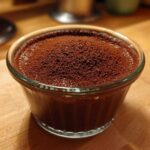 Close-up of rich Vegan Chocolate Avocado Mousse topped with cocoa powder in a glass ramekin.