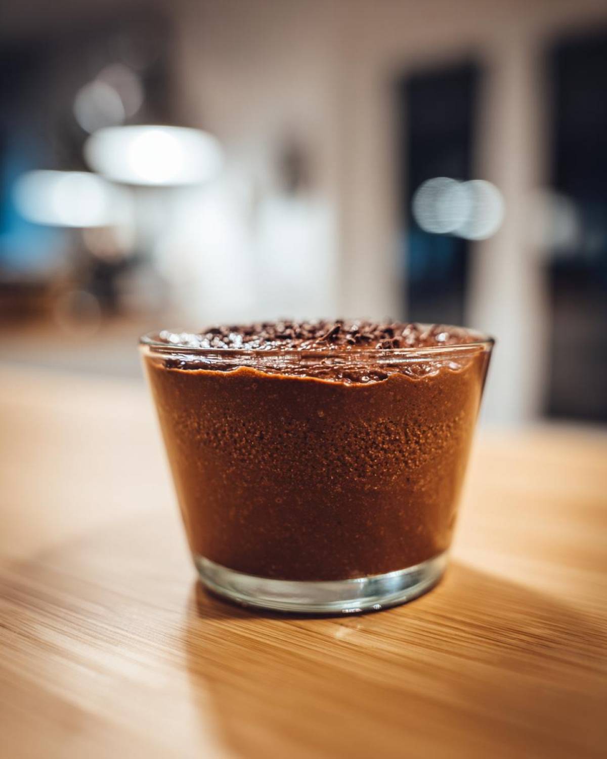 Close-up of rich Vegan Chocolate Avocado Mousse topped with chocolate shavings in a small glass.
