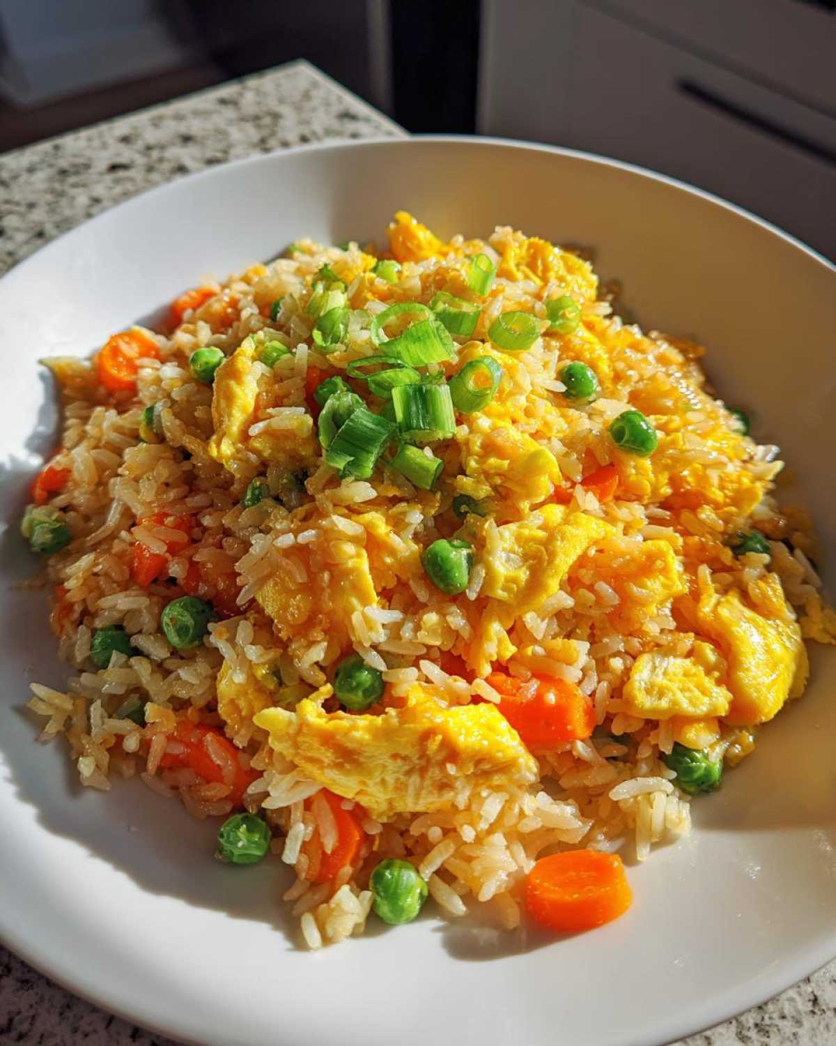 Close-up of vibrant Vegetable Fried Rice featuring scrambled eggs, peas, carrots, and green onions.