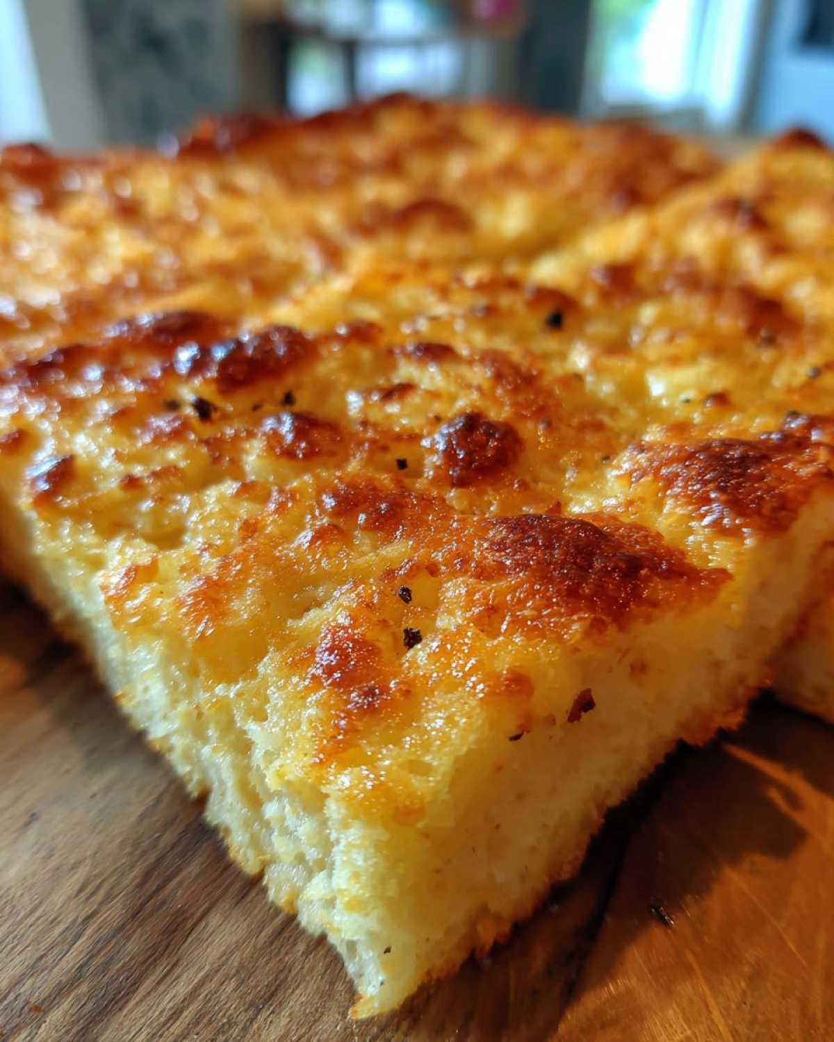 Close-up of a thick, golden brown slice of keto pizza crust showing a cheesy, baked top.