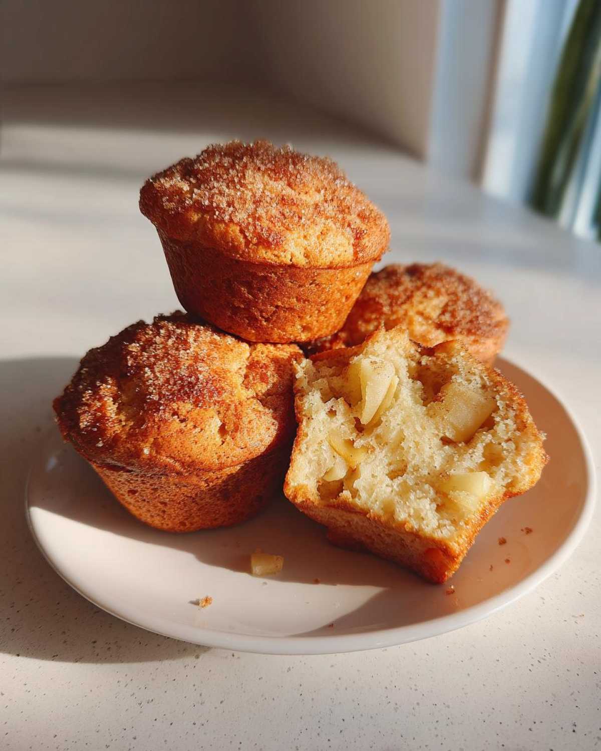 Close-up of Apple Cinnamon Greek Yogurt Muffins, one broken open to show apple chunks inside.