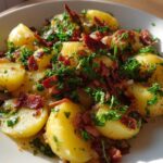 Close-up of Authentic German Potato Salad featuring warm, waxy potatoes tossed with crispy bacon bits and fresh parsley.