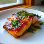 A perfectly cooked fillet of Baked Honey Garlic Salmon, glistening with a sweet glaze and topped with fresh parsley.