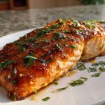 A perfectly cooked fillet of baked honey garlic salmon with a shiny glaze and fresh parsley.