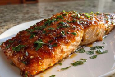 A perfectly cooked fillet of baked honey garlic salmon with a shiny glaze and fresh parsley.