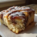 Close-up of a soft, glazed portion of Banana Bread Batter Cinnamon Buns, showing the swirl and icing.