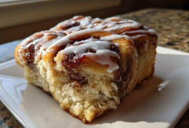 Close-up of a soft, glazed portion of Banana Bread Batter Cinnamon Buns, showing the swirl and icing.
