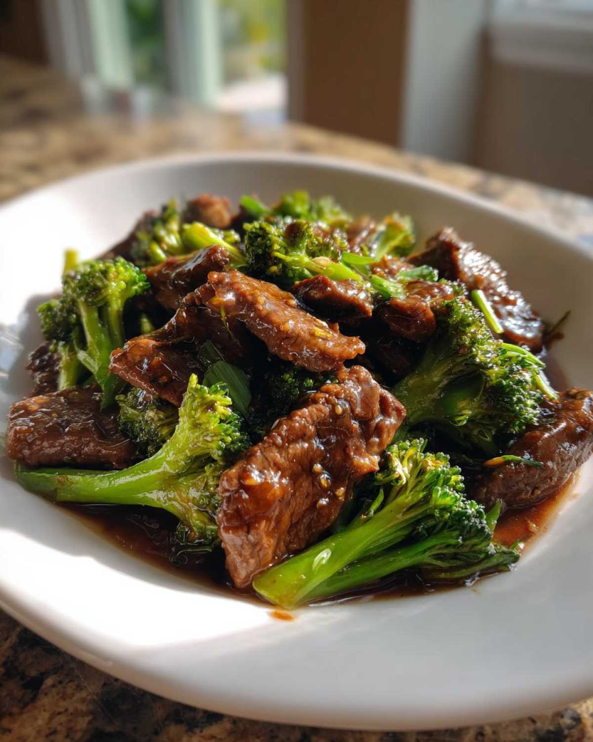 A close-up shot of tender slices of Beef and Broccoli Stir Fry coated in a rich, dark sauce, served in a white bowl.