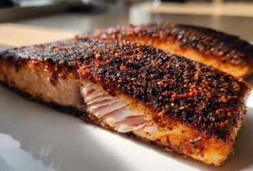 Close-up of a juicy salmon fillet with a thick, dark, spicy crust from the blackened salmon seasoning.