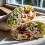 Cross-section view of a chicken bacon ranch wrap filled with shredded chicken, crispy bacon, lettuce, and ranch dressing.