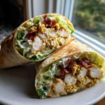 Two halves of a delicious chicken bacon ranch wrap cut open, showing crispy chicken, bacon, lettuce, and ranch dressing.