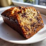 Close-up of a moist slice of The Chocolate Chip Banana Bread So Moist! loaded with melted chocolate chips.