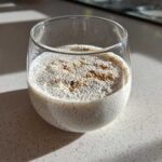 Close-up of a serving of coconut chia pudding topped with cinnamon in a clear glass.