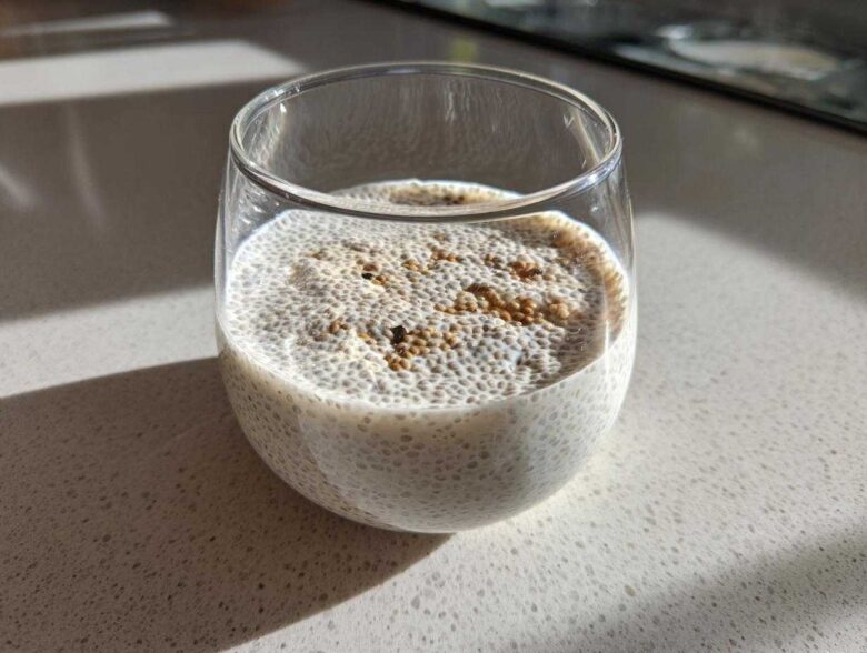 Close-up of a serving of coconut chia pudding topped with cinnamon in a clear glass.