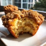 Close-up of a Coffee Cake Muffin with Crumble Magic, showing a bite taken out revealing the moist interior and cinnamon swirl.