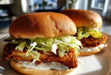 Two Crispy Chicken Sandwich Dill Aioli sandwiches featuring fried chicken, shredded lettuce, pickles, and creamy dill aioli on toasted buns.