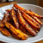 Close-up of perfectly crispy, glazed sweet potatoes fries piled high in a white bowl.