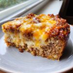 Close-up of a thick slice of crockpot french onion meatloaf topped with melted golden and white cheese.