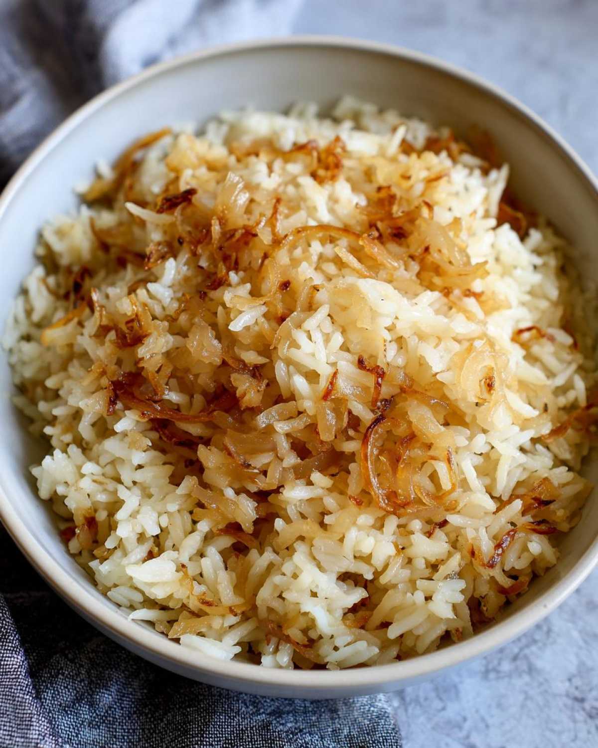 A close-up of fluffy white rice topped generously with caramelized, crispy french onion butter rice topping.