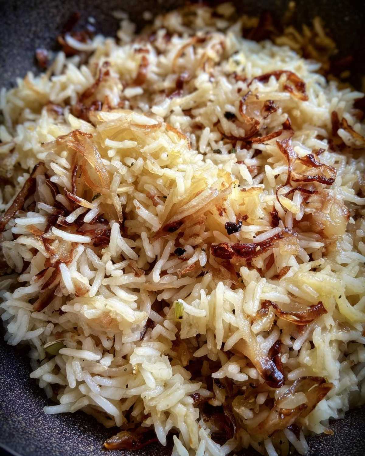 Close-up shot of fluffy white rice mixed with caramelized, crispy onions, showcasing the french onion butter rice.