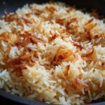 A close-up shot of fluffy white rice topped generously with crispy, caramelized onions, showcasing the french onion butter rice.