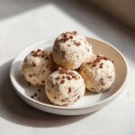 Four creamy Frozen Peanut Butter Greek Yogurt Bites dusted with crumbs, served on a small, light-colored bowl.
