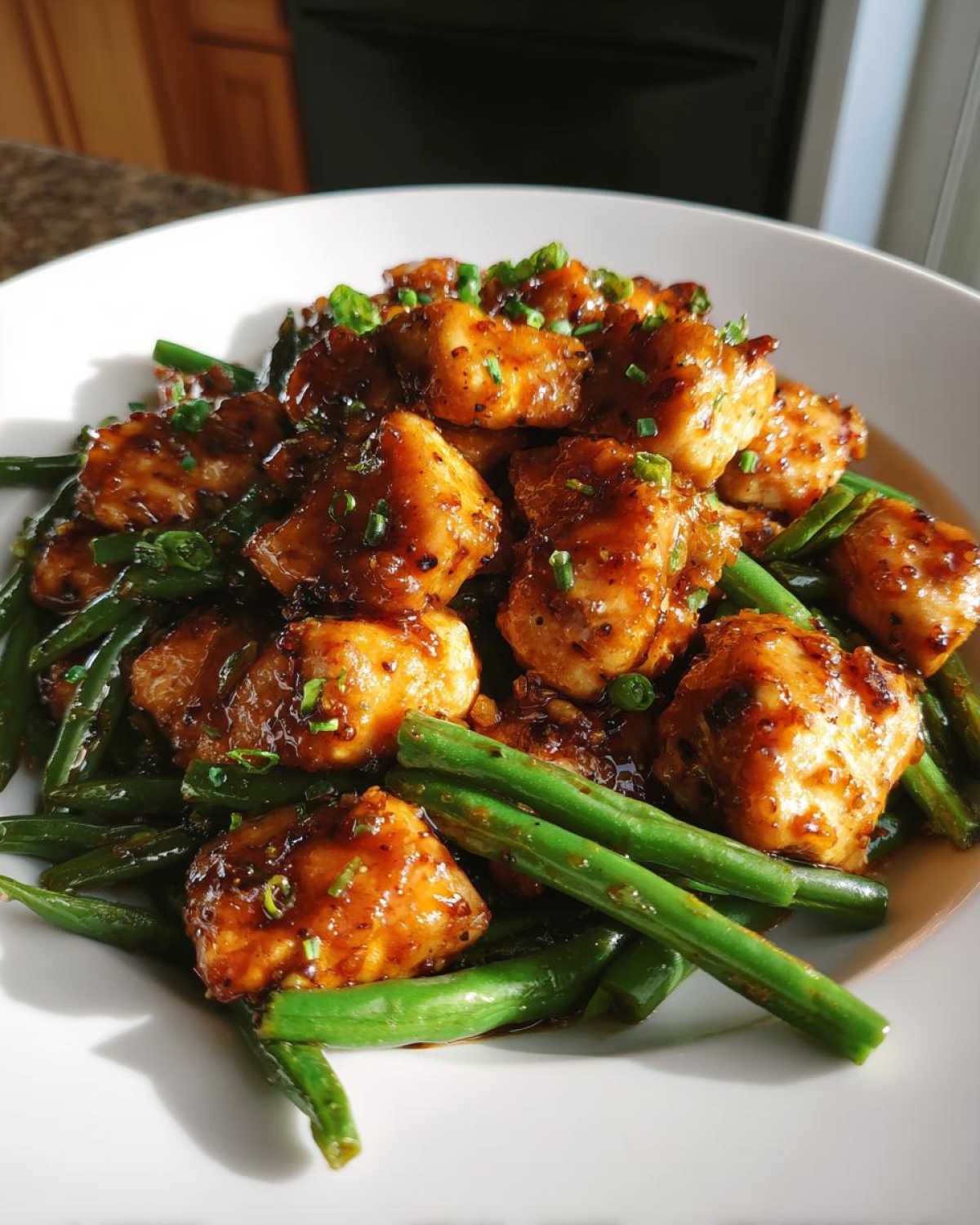 Close-up of glazed chicken pieces served over bright green beans, a delicious chicken and green beans dinner.