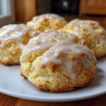 Four freshly baked Italian ricotta cookies topped with a thick, glossy glaze, sitting on a white plate.