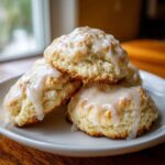 A stack of three fluffy Italian ricotta cookies generously topped with a sweet white glaze.