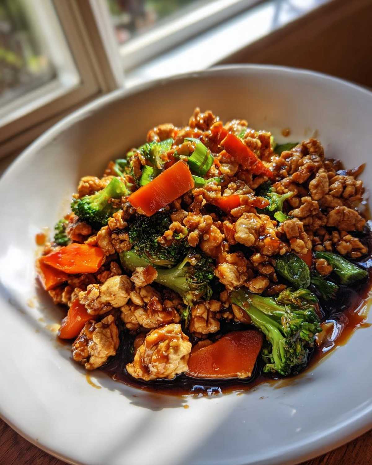 Close-up of Ground Chicken Teriyaki Stir Fry with broccoli and carrots in a white bowl.