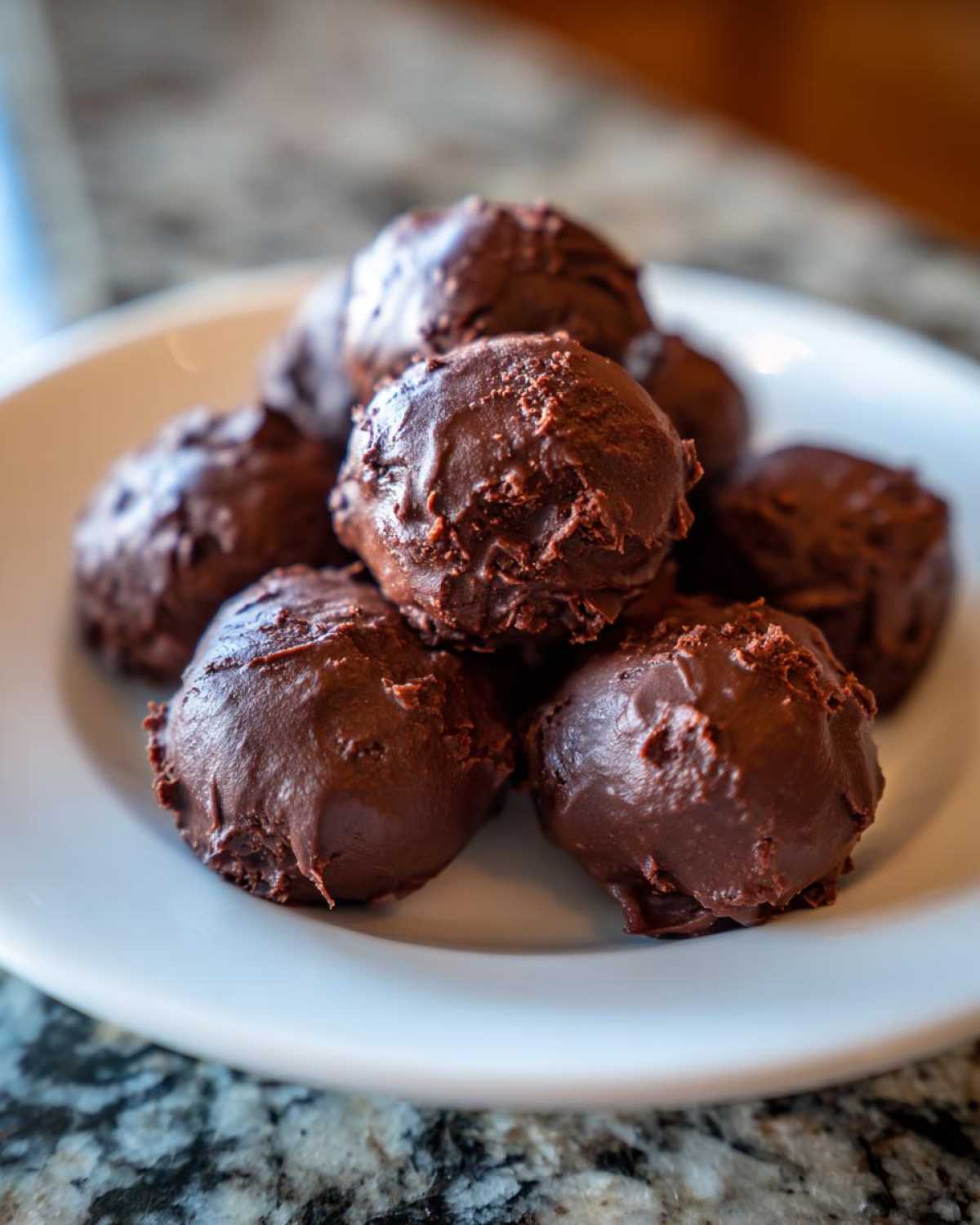 A pile of rich, chocolate-coated homemade Oreo balls stacked on a white plate.