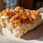 A square serving of creamy hot chicken salad bake topped with a thick layer of golden, crunchy cornflakes.