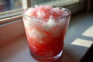 Close-up of a frosty glass filled with icy, layered Irresistible Strawberry Piña Colada Punch.