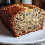 Close-up of a slice showing the moist crumb texture of Incredibly Moist Banana Bread on a white plate.