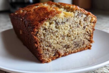 Close-up of a slice showing the moist crumb texture of Incredibly Moist Banana Bread on a white plate.
