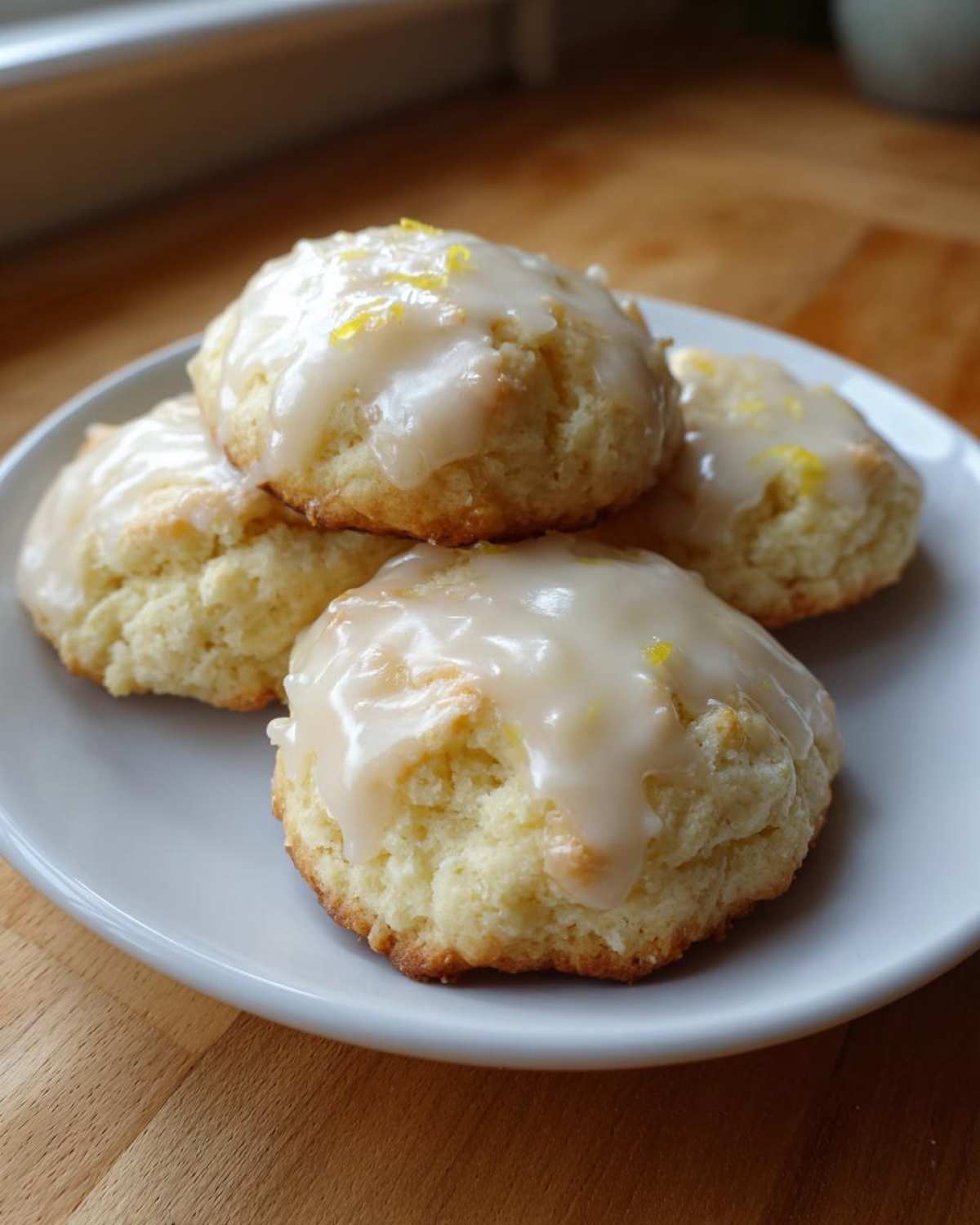 Four soft, round Italian ricotta cookies topped with a thick lemon glaze and zest.