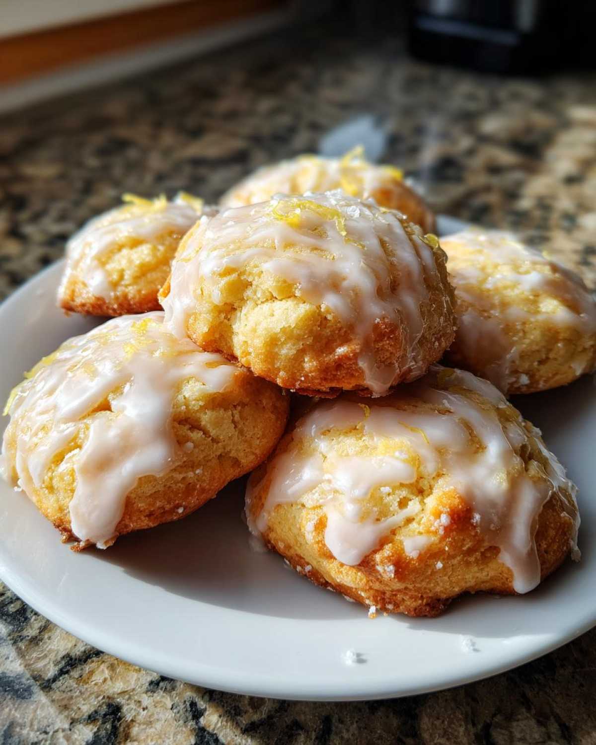 A stack of soft Italian ricotta cookies drizzled with lemon glaze and topped with zest.