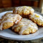 A stack of soft Italian ricotta cookies drizzled with white lemon glaze and topped with zest.