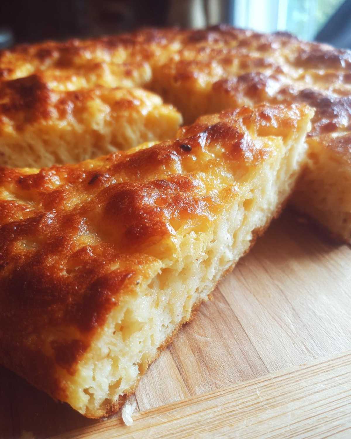 Close-up of a thick, golden brown slice of keto pizza crust showing its fluffy interior texture.
