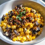 Close-up of Mexican Street Corn Salad MushroomSalus featuring creamy corn, dark mushrooms, and a sprinkle of red spice.