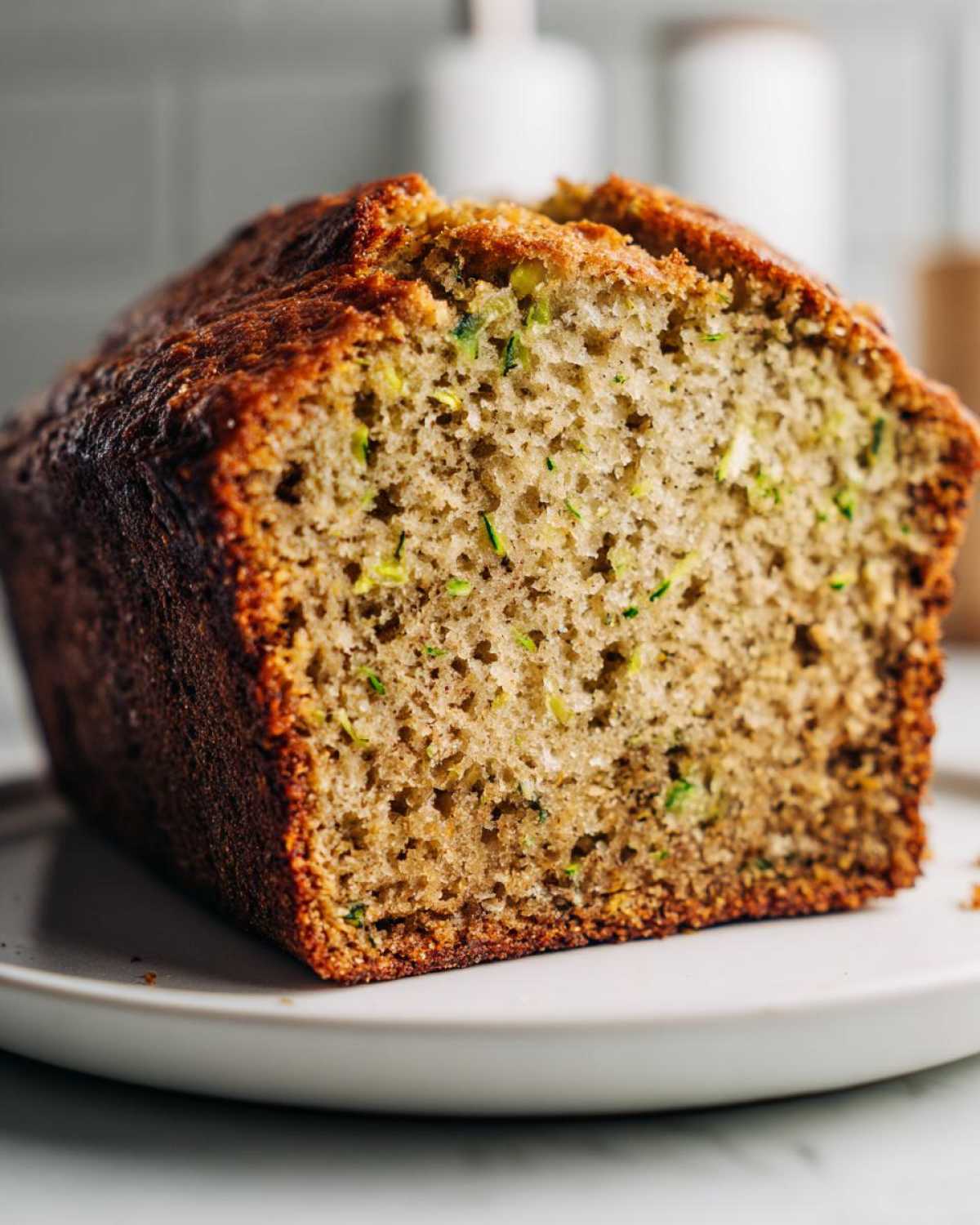 Close-up of a slice of moist zucchini banana bread showing the soft crumb and flecks of green zucchini.