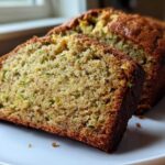 Two thick slices of moist zucchini banana bread showing the tender crumb and flecks of green zucchini.
