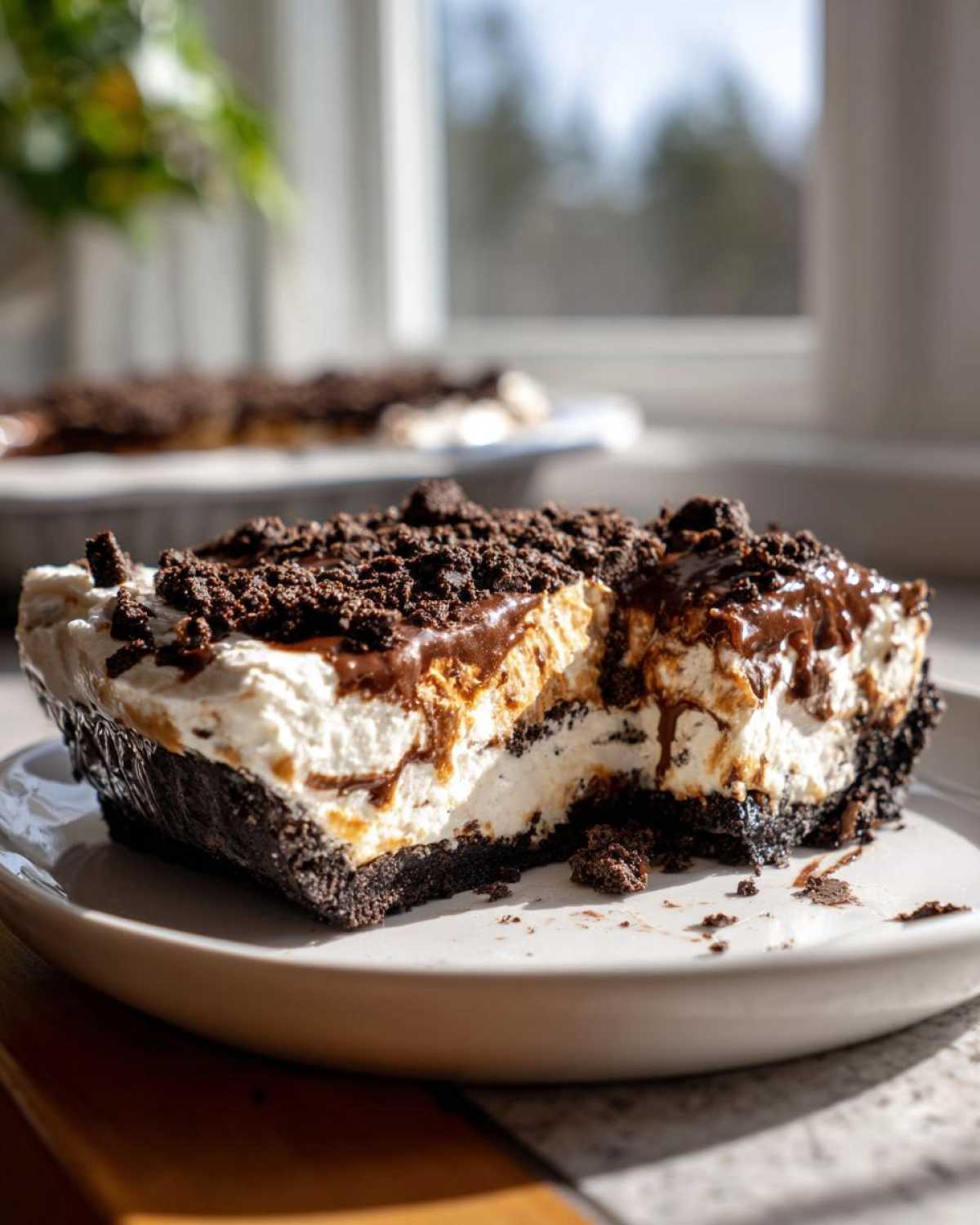 Close-up of a rich slice of no bake oreo pie showing creamy filling, chocolate drizzle, and cookie crumble topping.