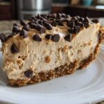 A close-up slice of creamy no bake peanut butter pie with a graham cracker crust, topped generously with chocolate chips.