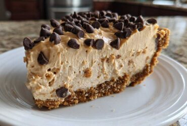 A close-up slice of creamy no bake peanut butter pie with a graham cracker crust, topped generously with chocolate chips.