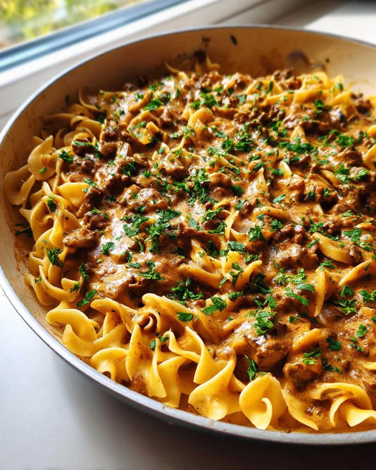 Close-up of One Pan Ground Beef Stroganoff with egg noodles and creamy sauce, garnished with parsley.