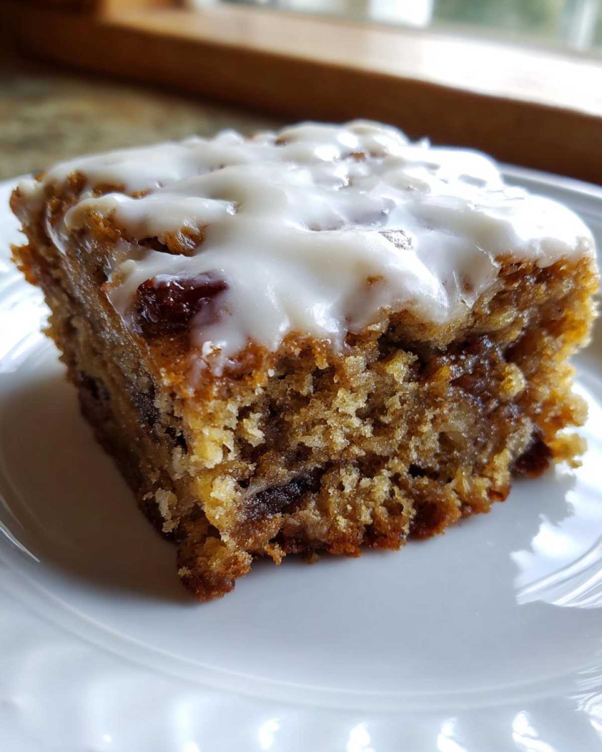 A close-up of a soft, moist square of Ooey Gooey Banana Bars topped with a thick white glaze.