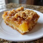 A close-up of a square slice of Paula Deen Pineapple Casserole with a gooey, caramelized topping and visible pineapple chunks.