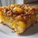 Close-up of a moist slice of Paula Deen Pineapple Casserole featuring chunks of pineapple and a brown sugar crumb topping.